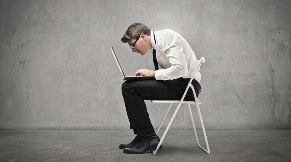 Mężczyzna siedzący w nieprawidłowej pozycji przy komputerze